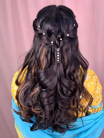 The final mehndi hairstyle, featuring a twisted half-up design with scattered pearls and soft curls.