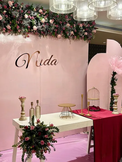 A detail shot of the dessert table area for Nida's birthday, featuring a clean white table, gold accents, and a beautiful floral runner overhead.