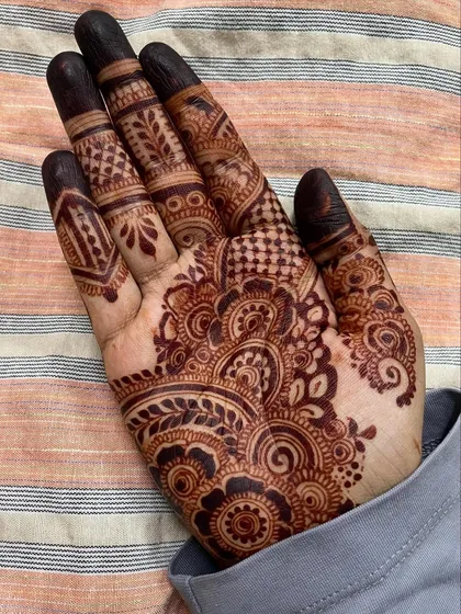 A rare design on my own right hand. This piece focuses on a dense cluster of floral and paisley patterns on the palm, with detailed work on the fingers.