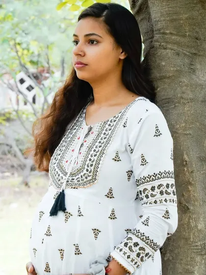 A profile shot of an expectant mother in a park setting. The natural light and serene environment create a timeless maternity portrait.
