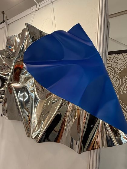 A new work from the Meteor series, featuring a bold blue element layered over a crumpled silver steel form, seen here at an art exhibition.
