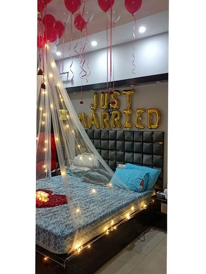 This view shows the "Just Married" foil balloons placed above the headboard, framed by the glowing fairy light canopy.
