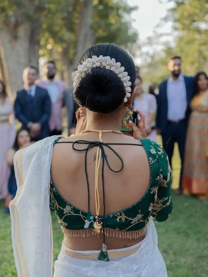 A detail shot of the bride's back, showcasing her elegant blouse design and the traditional gajra in her hair bun. A beautiful capture of South Indian bridal style.