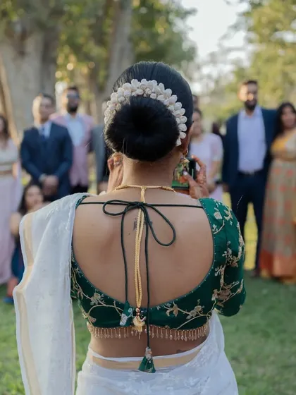 A detail shot of the bride's back, showcasing her elegant blouse design and the traditional gajra in her hair bun. A beautiful capture of South Indian bridal style.