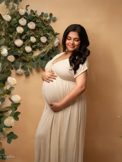 Surrounded by a wreath of white roses, this mama-to-be looks like she's in her own secret garden. A truly romantic setup.