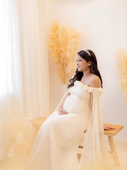A seated portrait that creates a serene and regal mood, with the mom-to-be looking thoughtfully out the window.