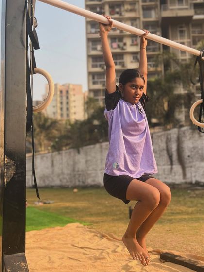 A young athlete practicing her dead hang during a morning session. The outdoor park provides a great environment for training.
