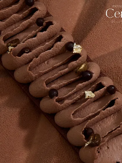 A close-up of the piped detail on the Mochaccino, adorned with chocolate pearls and gold leaf.