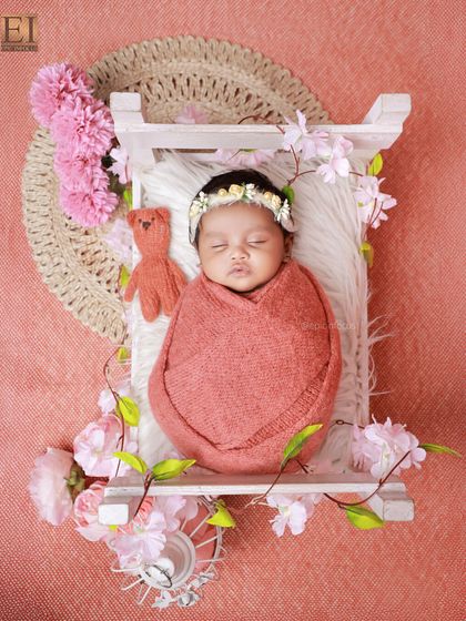 An overhead view of the floral bed setup, showing the baby sleeping peacefully with a tiny teddy bear.