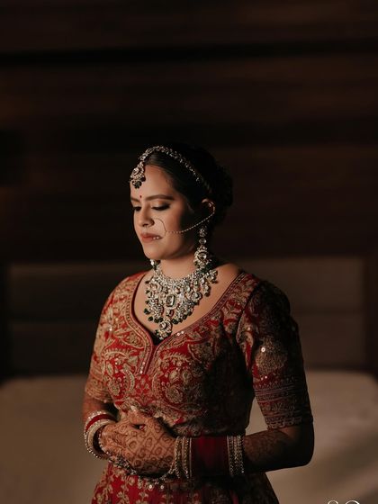 A moment of quiet reflection. The soft lighting highlights the beautiful contouring and the richness of her bridal attire.