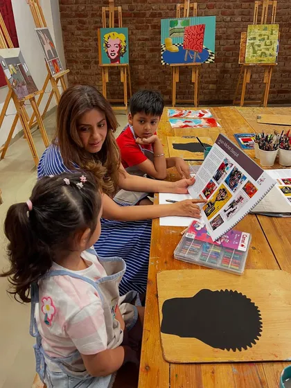 An instructor introduces our youngest artists to the world of Western Art, using a book to show examples before they begin their own creations.