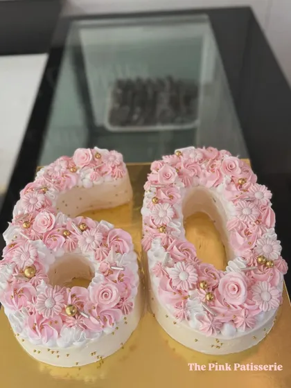 A close-up of the beautiful "60" monogram cake, showing the detailed piping work of the buttercream flowers and the delicate gold bead accents.