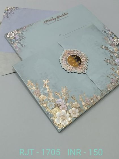 This gate-fold card in a soft blue is adorned with 3D flowers and gold foil accents. The design is delicate and pretty, with a central monogram for personalization.