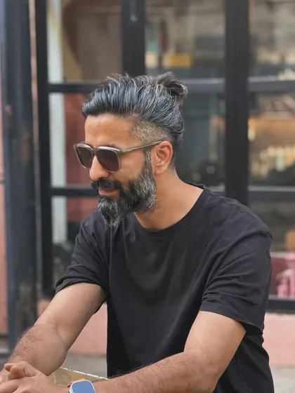 The man bun style, tied back neatly. This is a practical and stylish option for managing longer hair.