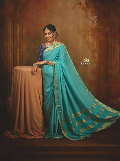 The light blue saree contrasts beautifully with the warm, classic backdrop. This is a wonderful example of a traditional yet soft maternity portrait.