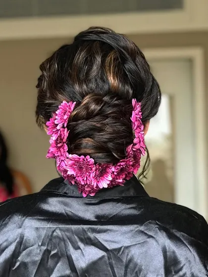 A behind-the-scenes look at the floral arrangement for the bun, using fresh magenta flowers to create a beautiful garland.