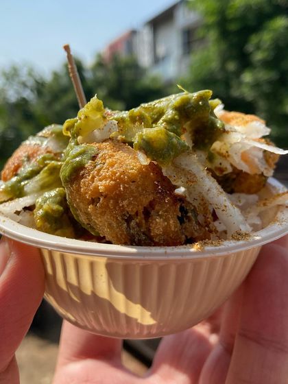 Ram Laddoo, a popular Delhi street food snack. These are soft moong dal fritters, deep-fried and topped with grated radish and tangy green chutney.