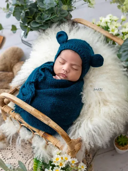 All wrapped up and cozy in a deep teal swaddle with a cute bear bonnet. Swaddling helps newborns feel secure and allows me to capture these adorable, womb-like poses.
