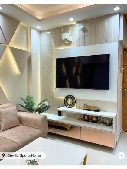 A modern TV unit with a geometric, backlit accent wall. The combination of neutral tones and gold trim creates a sophisticated and visually interesting focal point.