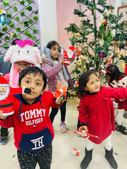 A group of kids showing off their Santa crafts, all dressed in festive red for the Christmas party.