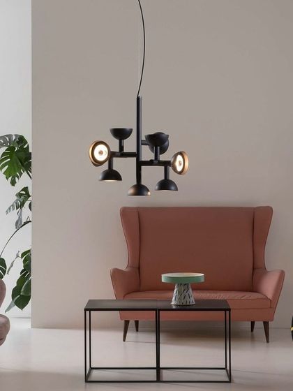 The smaller version of the Sibilla chandelier hangs in a colorful living room, its sculptural form holding its own amongst other design pieces.