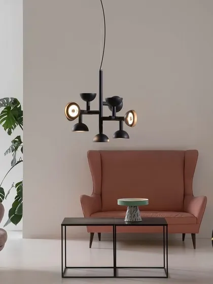 The black Sibilla chandelier in a colorful living room. The name is a tribute to the myth of the Sibyls, whose prophecies spread like the streams of light from this original suspension.