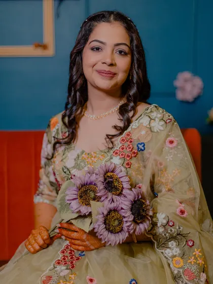 A beautiful portrait of the bride at her Mehendi, holding a bouquet of sunflowers. Her serene smile and lovely outfit are captured perfectly.