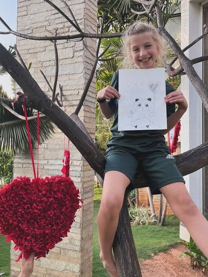 Another happy artist in a tree, proudly presenting her adorable panda drawing from our outdoor sketching session.