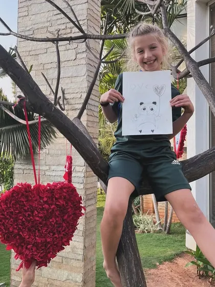 Another happy artist in a tree, proudly presenting her adorable panda drawing from our outdoor sketching session.