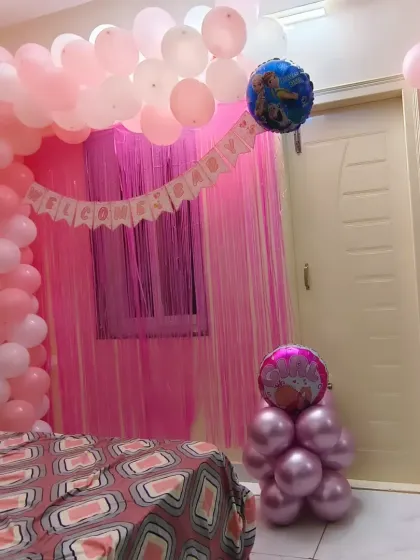 Another view of the pink-themed welcome home bedroom decoration, showing the full balloon arch and backdrop setup.