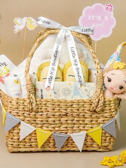 An 'It's a Girl' gift basket featuring a fairy doll and yellow and grey accents. The composition is balanced and visually pleasing.