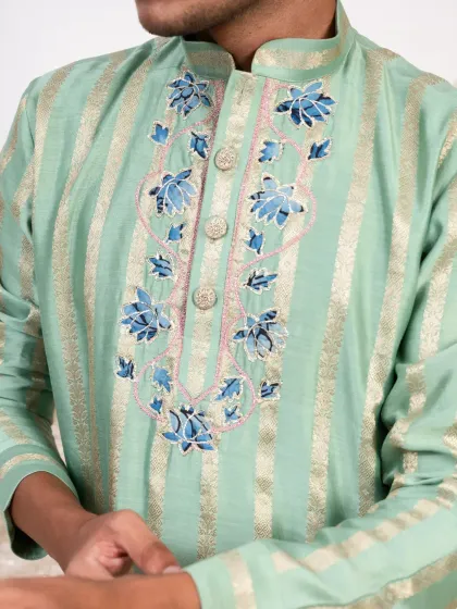 A close up of the intricate blue and pink threadwork on the mint green kurta. This detail adds a touch of artistry to the contemporary design.
