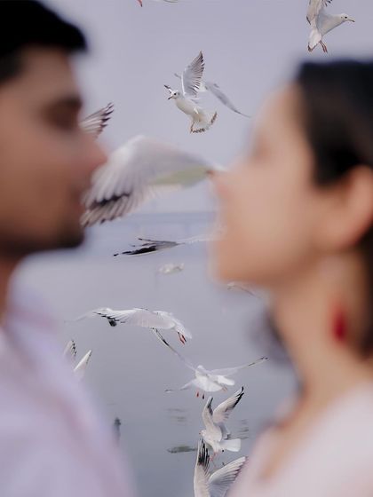 An artistic, out-of-focus shot where the birds flying between the couple are the main subject. This creative pre-wedding photography technique creates a dreamy and unique image.