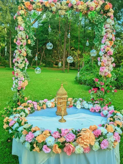 A beautiful floral frame setup in a lush green garden for a destination wedding, perfect as a photo booth or a small ceremony backdrop.