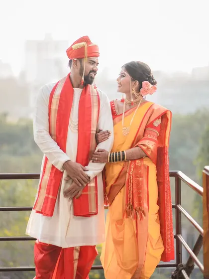 A classic wedding portrait of the couple standing together. This shot captures their full traditional Maharashtrian wedding attire against a soft, bright background, creating a timeless memory.