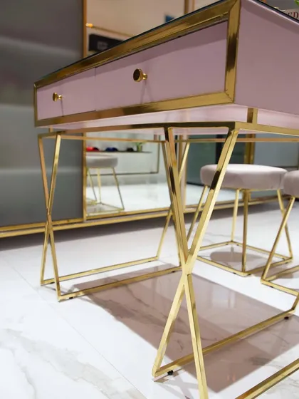 A detail shot of a custom work desk I designed for a retail store. The combination of a dusty pink top, a gold lacquered brass frame with a criss-cross leg design, and a glass surface creates a very chic and glamorous look.