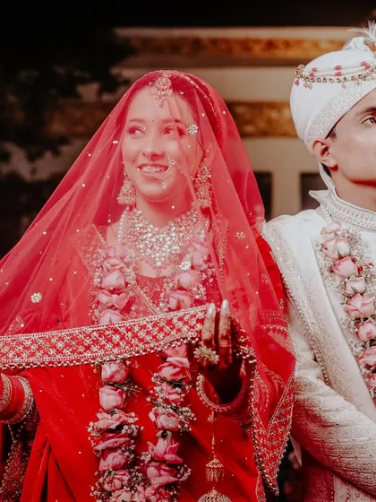 A happy, candid shot of the couple, with the bride's red veil adding a beautiful splash of color.