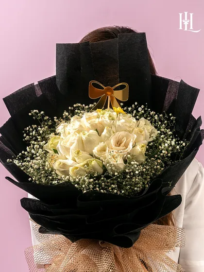 A symbol of purity and love, this white rose bouquet is an elegant and timeless Valentine's gift. The chic black wrapping makes the white blooms stand out beautifully.