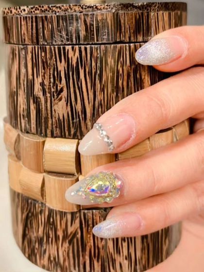 A close-up of the accent nails, highlighting the large, multi-faceted iridescent crystal and the line of silver rhinestones.