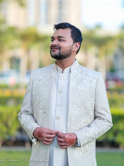 A handsome outdoor portrait of the groom in his elegant off-white engagement attire.
