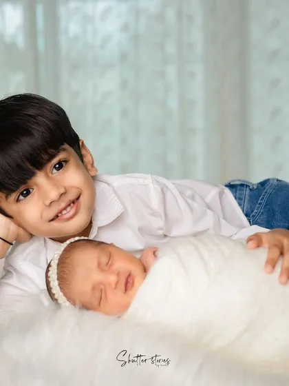 The love between siblings is so special. A proud big brother lies next to his sleeping newborn sister.