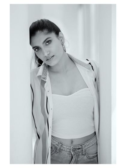A casual portrait in black and white. The natural light from the window and the relaxed pose give this image an authentic, lifestyle feel while maintaining a classic aesthetic.