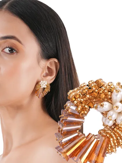 The Ninaara Gold Studs, with their open-hoop design and pearl flower centre, are a modern take on classic gold earrings.