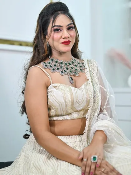 A close-up portrait showing an alternative jewellery pairing with the ivory lehenga. This features a stunning emerald and American diamond necklace.