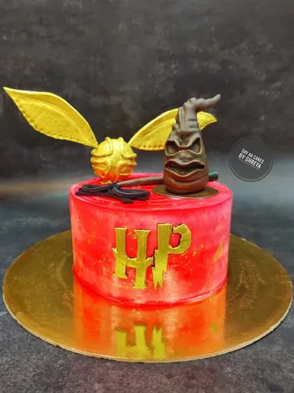 This magical Harry Potter cake features a Gryffindor-red theme. The edible, handcrafted Sorting Hat and Golden Snitch make it a spellbinding treat for any witch or wizard's birthday.