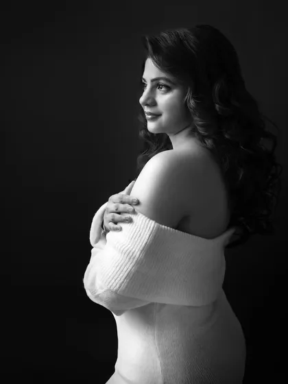 The same portrait in black and white. It creates a timeless, classic feel, focusing on her serene expression and the soft texture of the sweater.