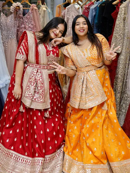 A fun pose from two friends in their bright and bold rental lehengas, showing the joy of dressing up together.