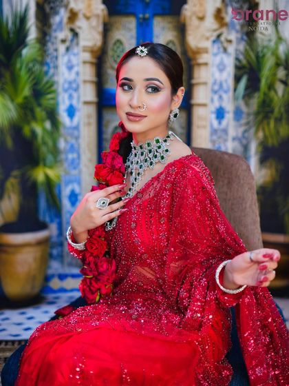 A graceful pose that captures the elegance of the bride, with attention to the detailed makeup and the rich red color palette.