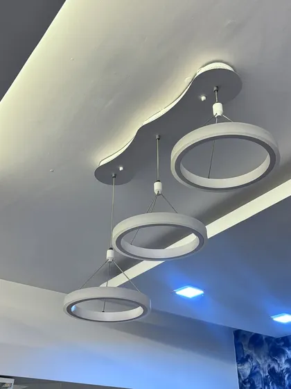 Another angle of the triple-ring chandelier, showing how it looks against the white false ceiling. The clean, modern design complements a minimalist interior style.