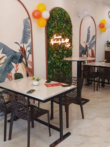 Here is the final look of the Rajarammundry Rose Milk cafe. We designed the space to feel bright and welcoming, using custom tropical murals, a vertical garden wall with a neon sign, and a mix of seating to create a cosy atmosphere for customers.